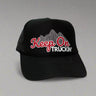 Black trucker hat with 'Keep On Truckin'' text and mountain graphic on a light gray background