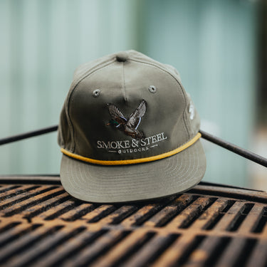 Green cap with gold rope with duck design and 'Smoke & Steel Outdoors' text Product Shot