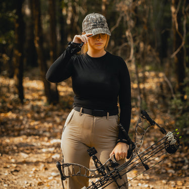 Mossy Oak Bottomland Camouflage cap with 'Timber & Tines' on model with a bow & arrow