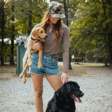 Old school duck camo cap with embroidered dog design on model with labrador retrievers