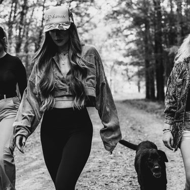 black & white photo woman in camo hat with Arkansas and black dog